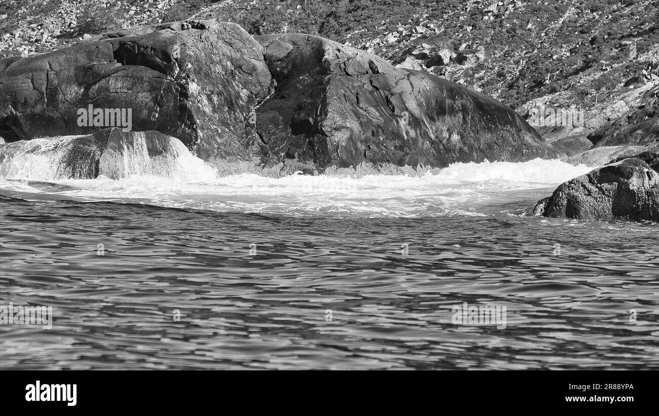 Norvegia sul fiordo, spruzzare sulle rocce in bianco e nero. Spruzzi d'acqua sulle rocce. Paesaggio costiero in Scandinavia. Foto del paesaggio da nord Foto Stock