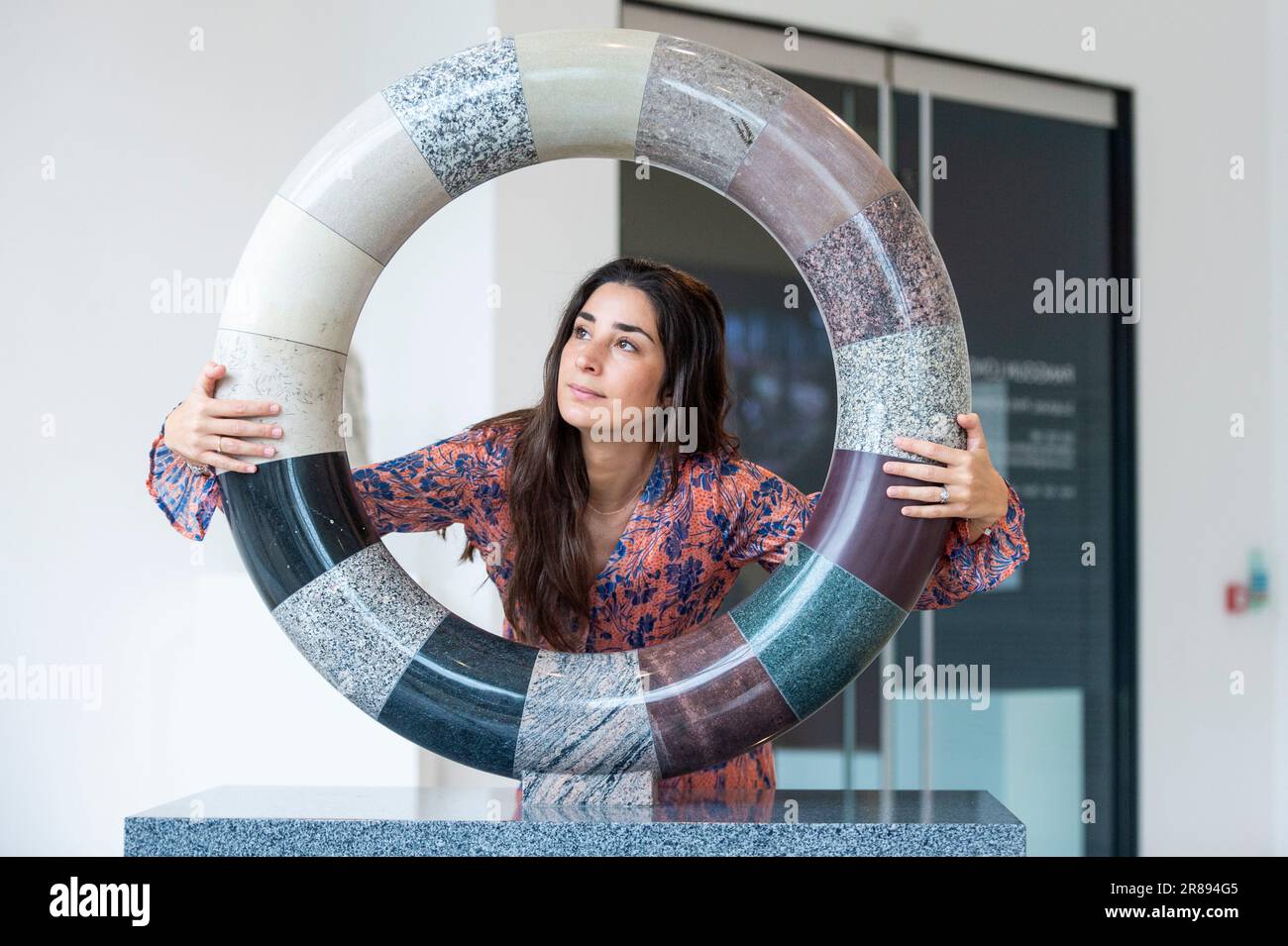 Londra, Regno Unito. 20 giugno 2023. Un membro dello staff con ‘Torus of Time’, 2023, sedici pietre che iniziano con gneiss lewisiano, di circa 3 miliardi di anni, in un’anteprima di ‘Deep Time: Uncovering Our Hidden Past’, una nuova mostra di scultura contemporanea di Angela Palmer alla Pangolin London Sculpture Gallery vicino a King’s Cross. I lavori esaminano la storia di tre miliardi di anni del Regno Unito attraverso le sue rocce e pietre. Lo spettacolo si svolge dal 21 giugno al 16 settembre. Credit: Stephen Chung / Alamy Live News Foto Stock