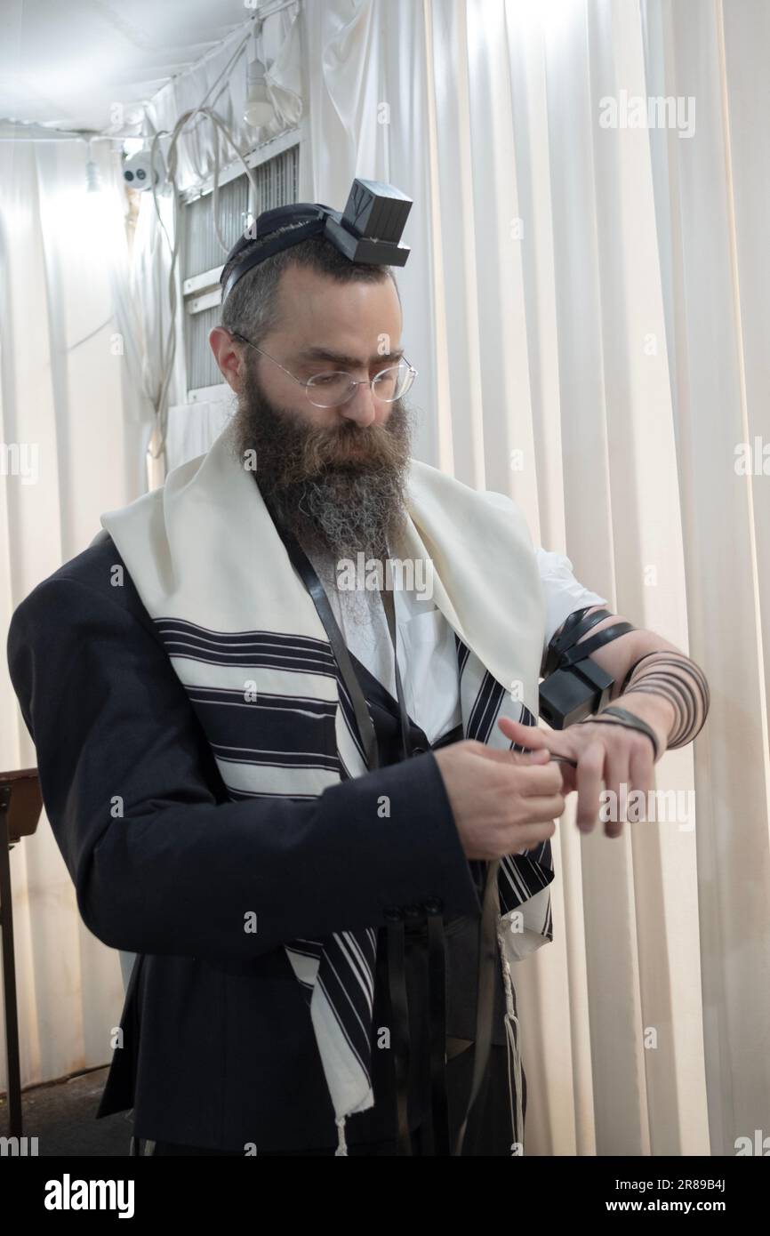 Un rabbino indossa i suoi tefillin - phylacteries - prima delle preghiere del mattino. In una sinagoga a Monsey, Rockland County, New York. Foto Stock