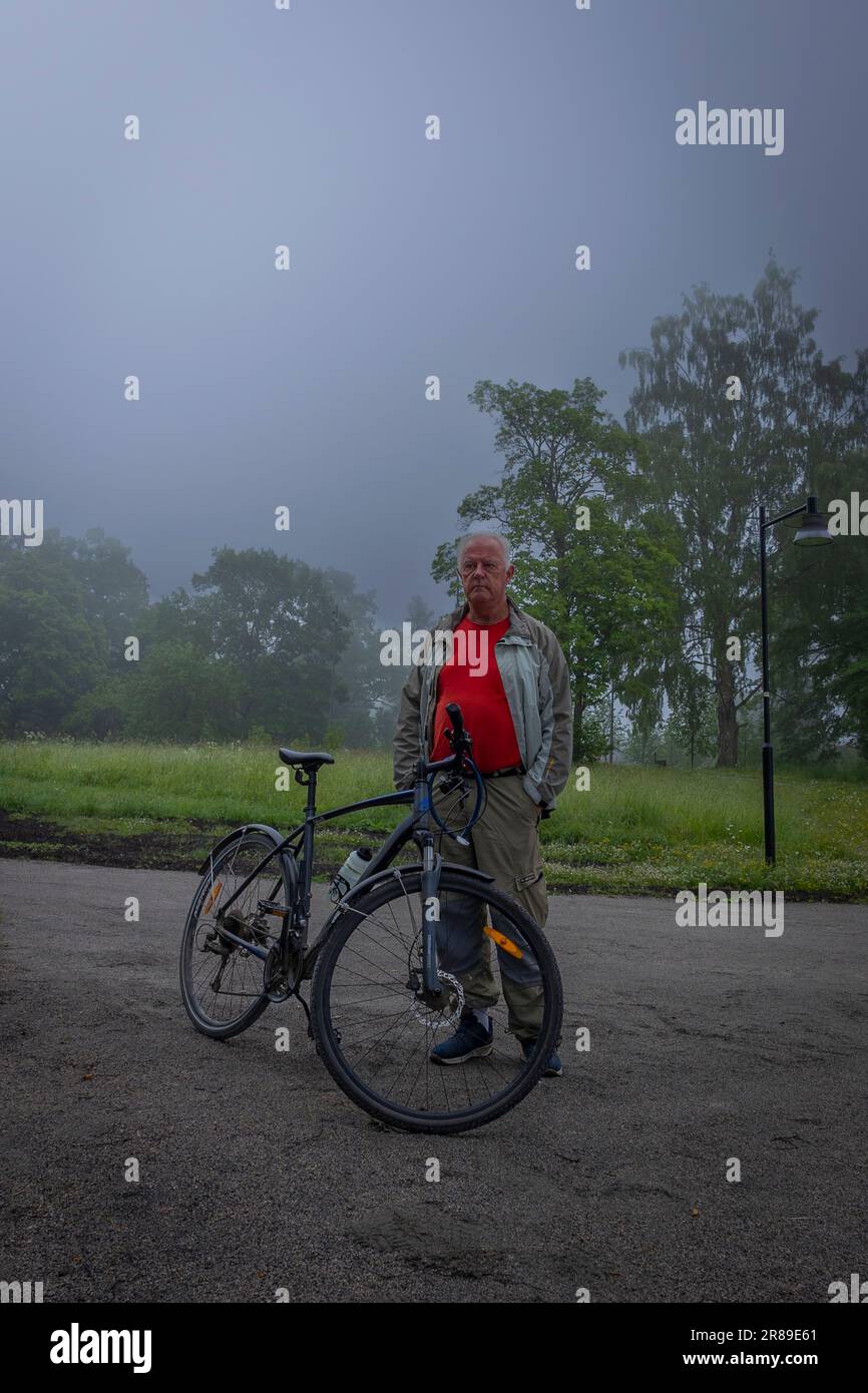 Uomo anziano con abiti casual guardando la nebbia sul lago Foto Stock