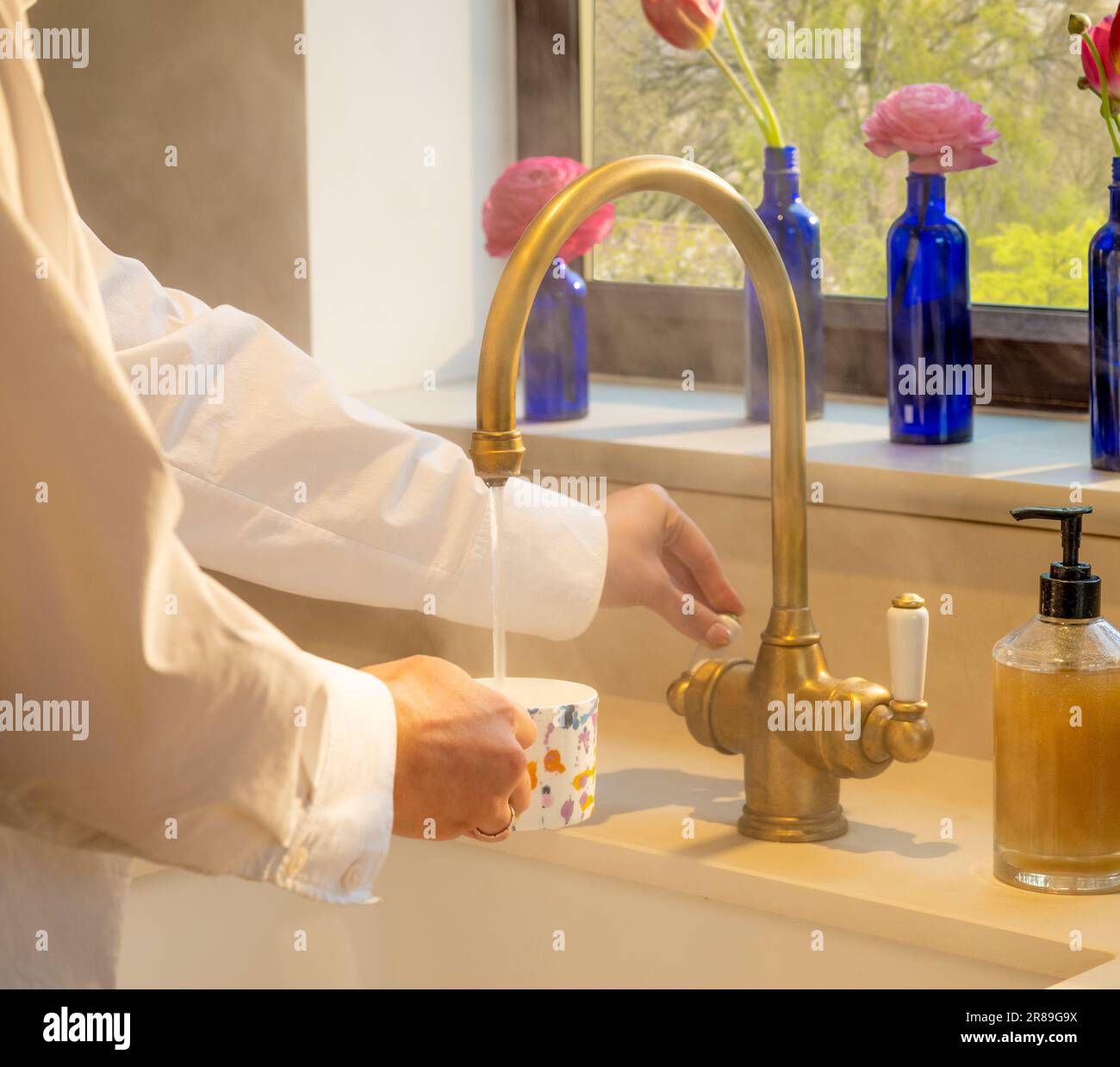 Primo piano delle mani in una cucina a vapore che prepara un drink con l'acqua di un rubinetto dell'acqua di una caldaia Foto Stock
