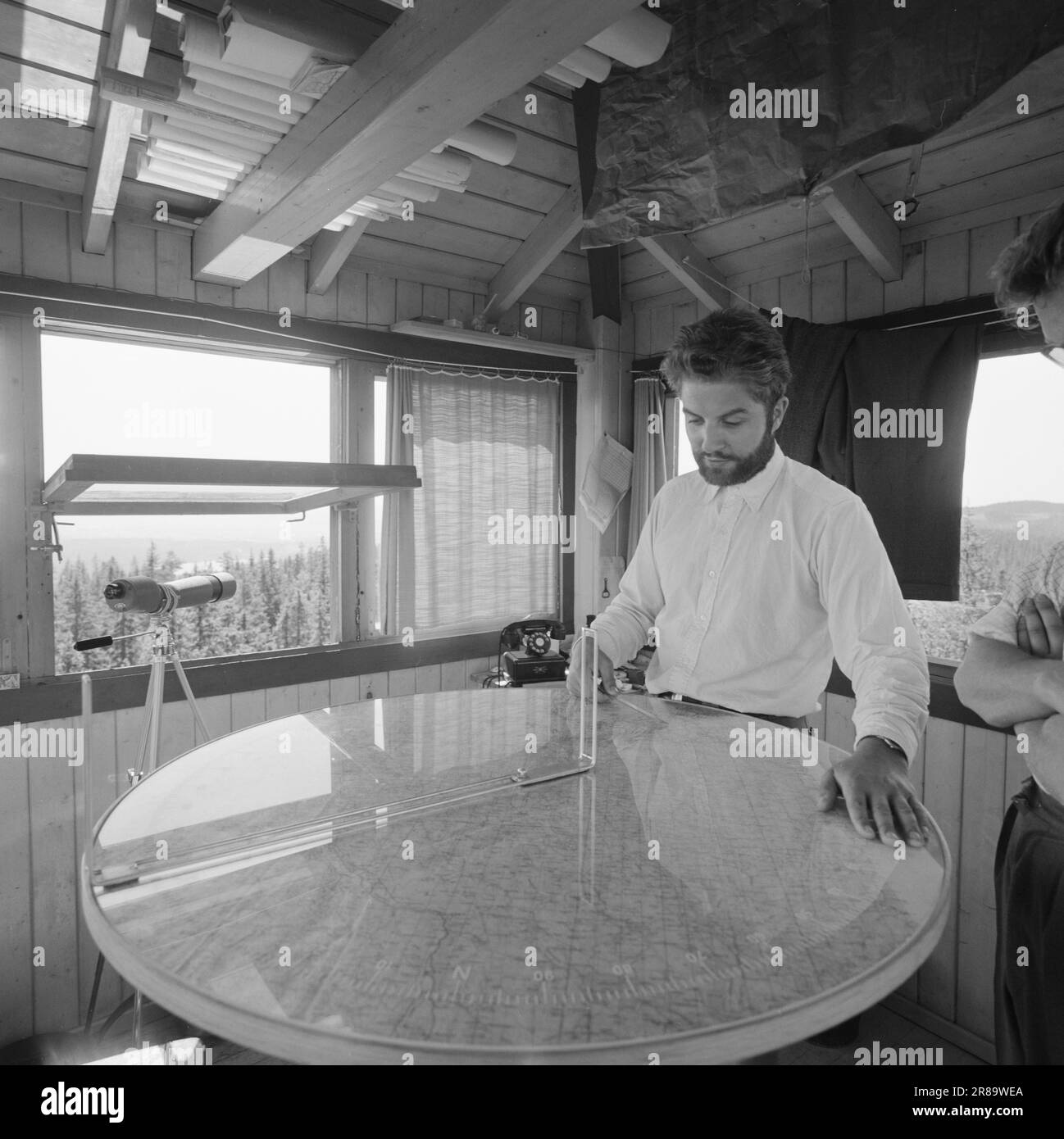 Attuale 29-6-1960: La sentinella solitaria abbiamo trovato un posto di lavoro strano. Giù là, un uomo che vive al suo posto cammina. Giorno e notte il nemico si aggirano, giorno e notte l'uomo solitario è in guardia - contro il fuoco della foresta. Stein Aanderaa, uno studente di teologia, ha un lavoro solitario di vacanza nella torre di guardia antincendio di Skgennungsåsen nelle foreste di Oslo. Alto e libero sopra le cime degli alberi, egli custodisce 5 miglia di foresta in tutte le direzioni. Al centro del pavimento nella sala di guardia, ha un tavolo con mappe e un dispositivo sonoro. È in servizio 24 ore su 24. Foto: Aage Storløkken / Aktuell / NTB ***FOTO NON IMA Foto Stock