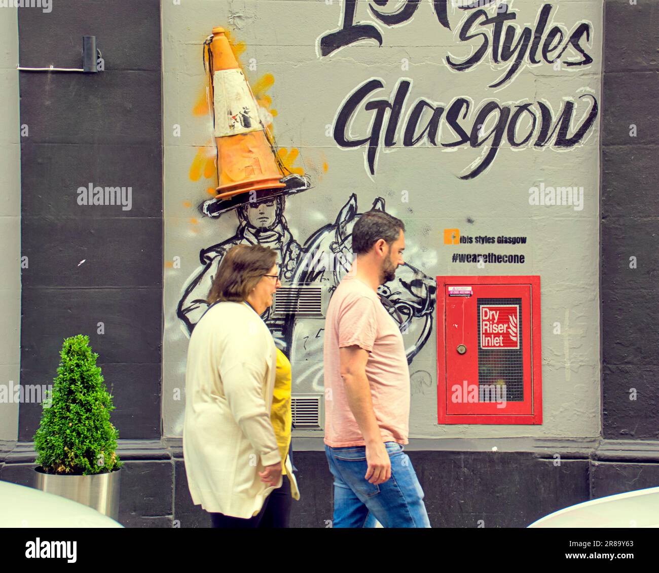 Glasgow, Scozia, Regno Unito 20th giugno 2023. Banksey cut and run continua al sole mentre le folle si affollano al museo di arte moderna L'iconica testa del cono, celebrata come il Goma e la statua del duca di Wellington nella piazza del cambio reale, si trova sulla facciata dell'hotel ibis Styles per i selfie turistici. Credit Gerard Ferry/Alamy Live News Foto Stock