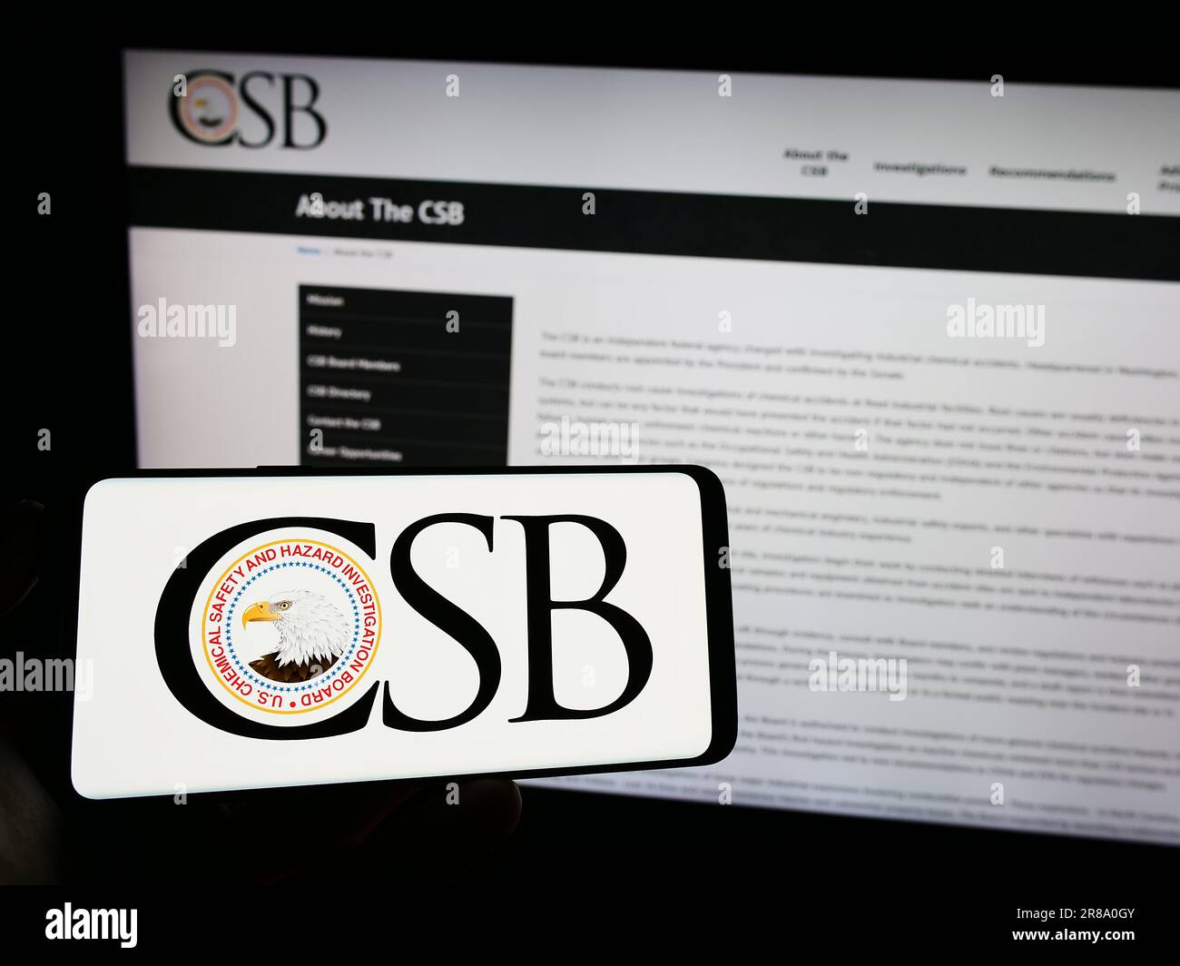 Persona che tiene il cellulare con il logo dell'agenzia federale americana USCSB sullo schermo davanti alla pagina Web. Concentrarsi sul display del telefono. Foto Stock