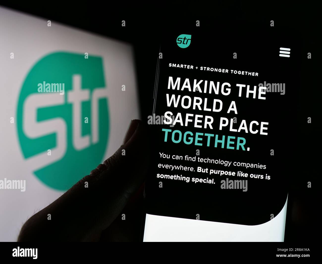 Persona che possiede uno smartphone con la pagina Web di Systems and Technology Research LLC (STR) sullo schermo davanti al logo. Concentrarsi sul centro del display del telefono. Foto Stock