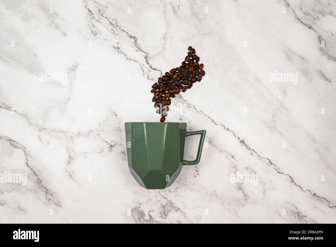 Vista dall'alto della tazza da caffè su sfondo di marmo bianco. I chicchi di caffè e la tazza verde sono piatti. Spazio di copia. Foto Stock