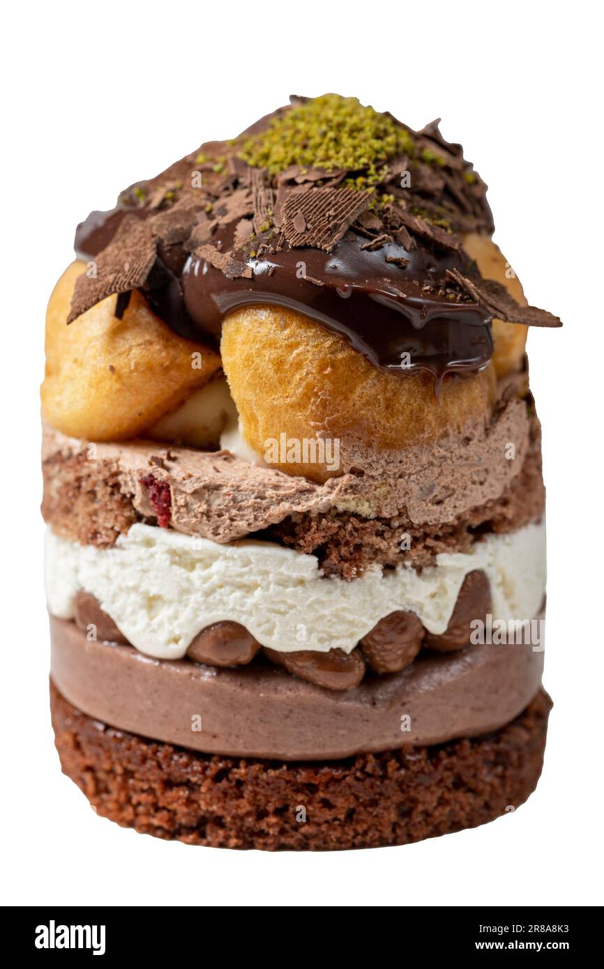 Torta a strati di profiteroles isolata su sfondo bianco. Panna montata, cioccolato e torta al pistacchio. Primo piano. Foto Stock
