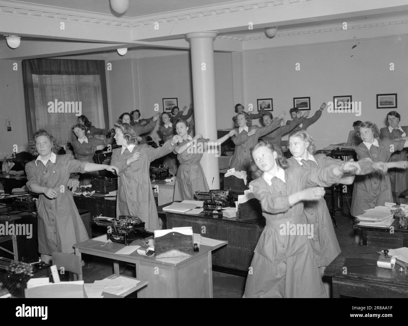 15-1947: Ginnastica durante l'orario di lavoro. C'è swing e ritmo nella ginnastica in ufficio a Storebrand di Oslo. In questa società, c'è stata ginnastica durante l'orario di lavoro sin dall'autunno del 1944. Per due anni, l'azienda ha avuto un 'ginnastica medica' dipendente in modo permanente, che conduce sia la normale ginnastica in ufficio che la ginnastica medica per i dipendenti che soffrono di dolore legato al lavoro. La ginnastica in ufficio si svolge per 13-14 ore e ogni festa viene sottoposta a un programma di dieci minuti. Sono stati raggiunti ottimi risultati, e lo sono sia il personale che la direzione aziendale Foto Stock