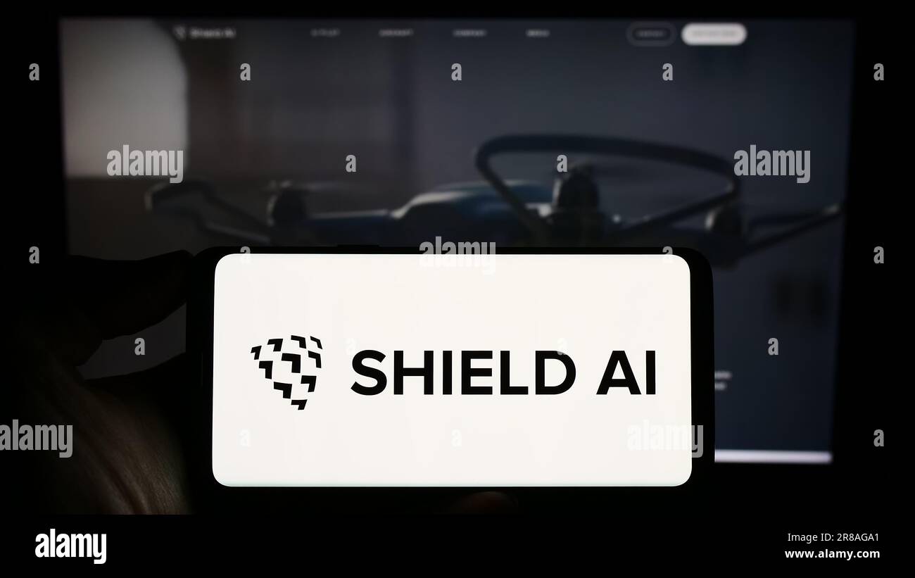 Persona che possiede un telefono cellulare con il logo della società americana per il settore aerospaziale e della difesa Shield ai sullo schermo davanti alla pagina Web. Concentrarsi sul display del telefono. Foto Stock