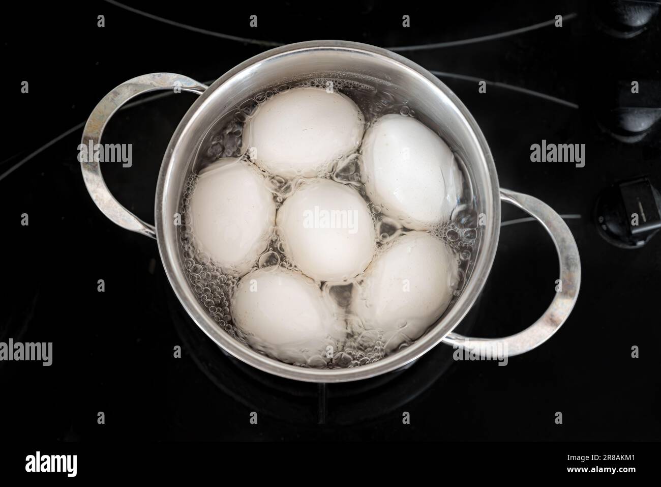 Le uova di pollo sono bollite in una pentola di acciaio sul fornello incorporato. Uovo bollito Foto Stock