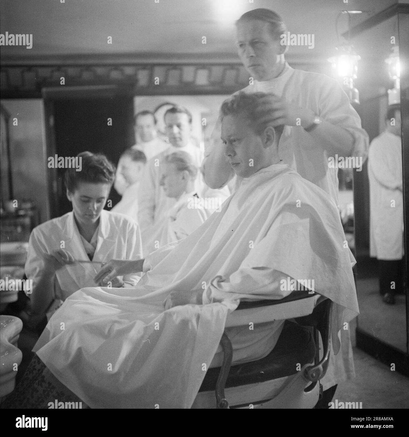 Corrente 22-1-1947: Il passato in un'ora di visitoPer un'ora ogni mattina, l'elettricità viene spenta a Oslo, come tanti altri luoghi del paese. A Oslo, il tempo di disconnessione è 11,30–12,30, in altri luoghi ci possono essere altri tempi. – L'interruzione dell'alimentazione provoca una significativa interruzione del lavoro per le aziende che dipendono dall'elettricità per le loro macchine. Cecil Barbersalong si trova su un piano seminterrato, ma la luce viene risparmiata grazie a numerose potenti lampade a cherosene. Tuttavia, i rasaerba elettrici devono essere azionati manualmente tra 11,30 e 12,30. Foto: TH. Skotaam / Aktuell / NTB Foto Stock