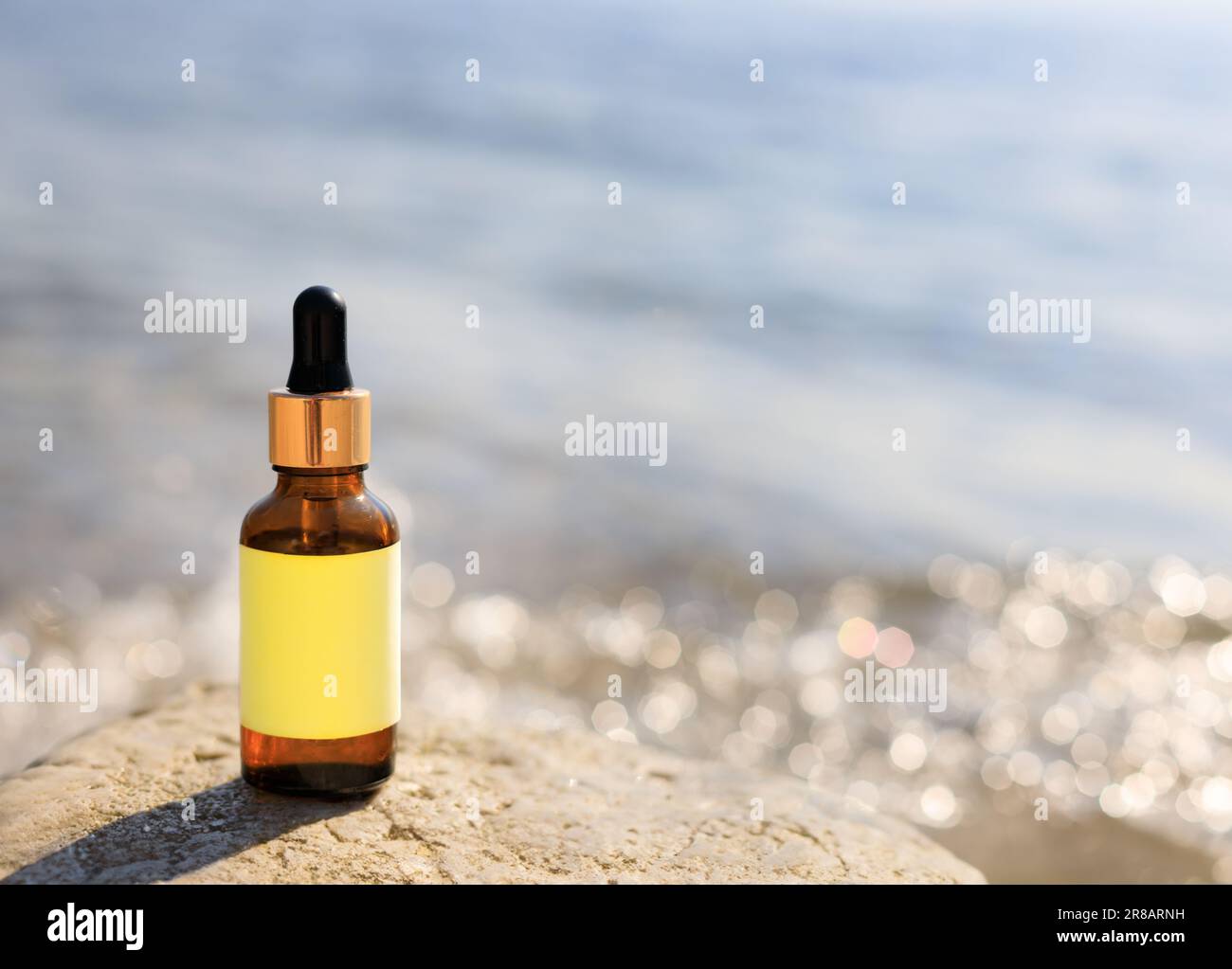 Bottiglia contagocce con sfondo sfocato della spiaggia. Cosmetica naturale o concetto di medicina. Foto Stock