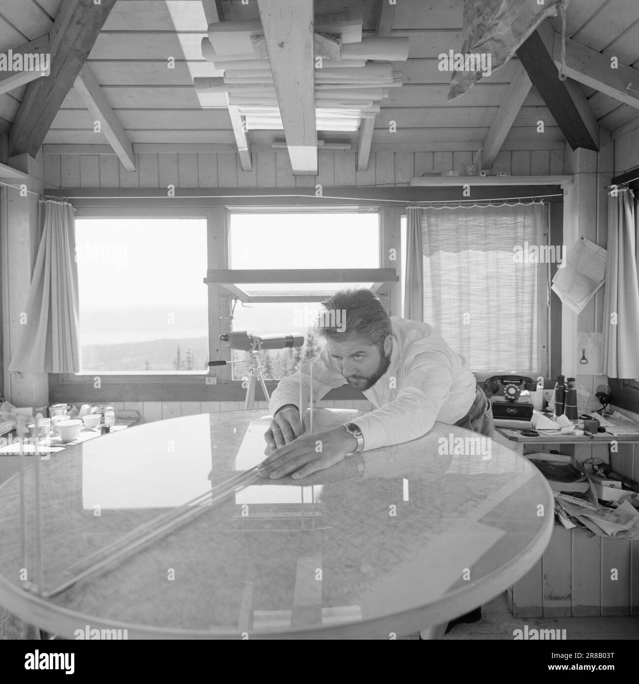 Attuale 29-6-1960: La sentinella solitaria abbiamo trovato un posto di lavoro strano. Giù là, un uomo che vive al suo posto cammina. Giorno e notte il nemico si aggirano, giorno e notte l'uomo solitario è in guardia - contro il fuoco della foresta. Stein Aanderaa, uno studente di teologia, ha un lavoro solitario di vacanza nella torre di guardia antincendio di Skgennungsåsen nelle foreste di Oslo. Alto e libero sopra le cime degli alberi, egli custodisce 5 miglia di foresta in tutte le direzioni. Al centro del pavimento nella sala di guardia, ha un tavolo con mappe e un dispositivo sonoro. È in servizio 24 ore su 24. Foto: Aage Storløkken / Aktuell / NTB ***FOTO NON IMA Foto Stock