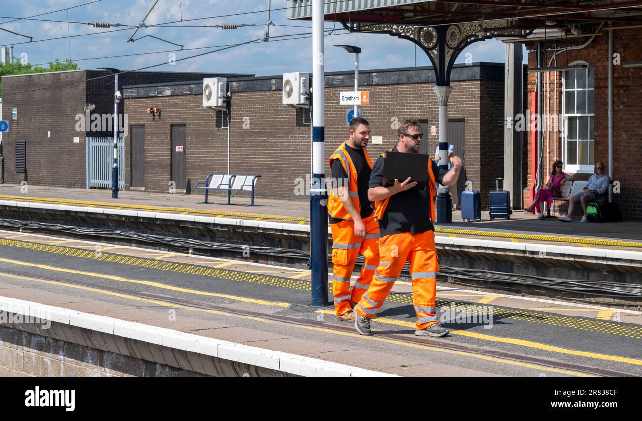 Stazione ferroviaria di Grantham – ingegneri ferroviari o personale addetto alla manutenzione che cammina lungo una piattaforma Foto Stock