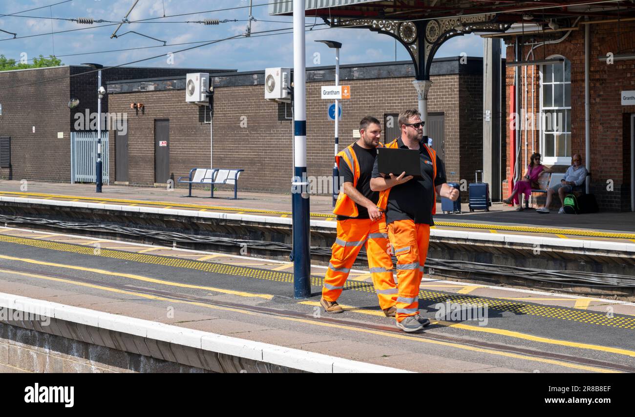 Stazione ferroviaria di Grantham – ingegneri ferroviari o personale addetto alla manutenzione che cammina lungo una piattaforma Foto Stock