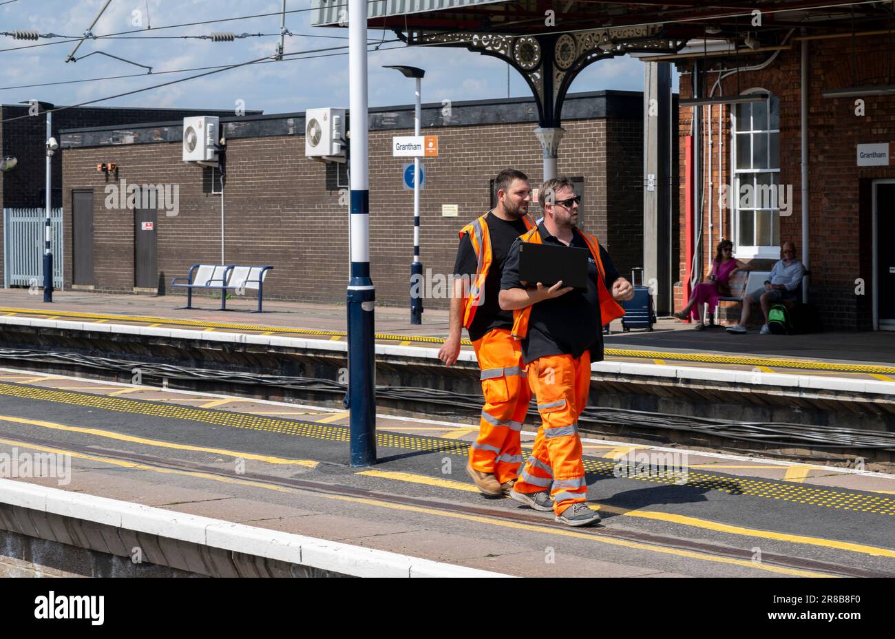 Stazione ferroviaria di Grantham – ingegneri ferroviari o personale addetto alla manutenzione che cammina lungo una piattaforma Foto Stock
