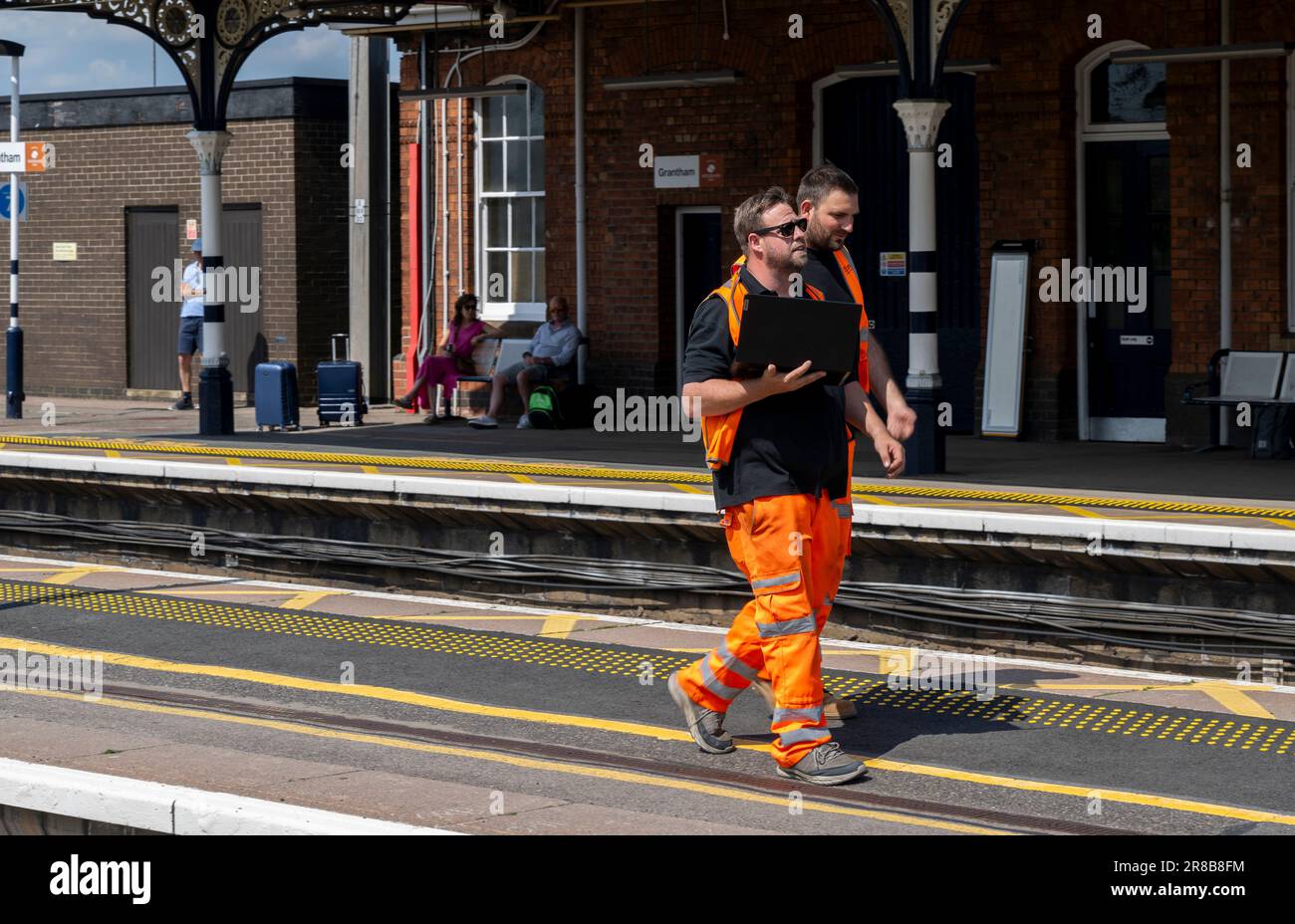 Stazione ferroviaria di Grantham – ingegneri ferroviari o personale addetto alla manutenzione che cammina lungo una piattaforma Foto Stock