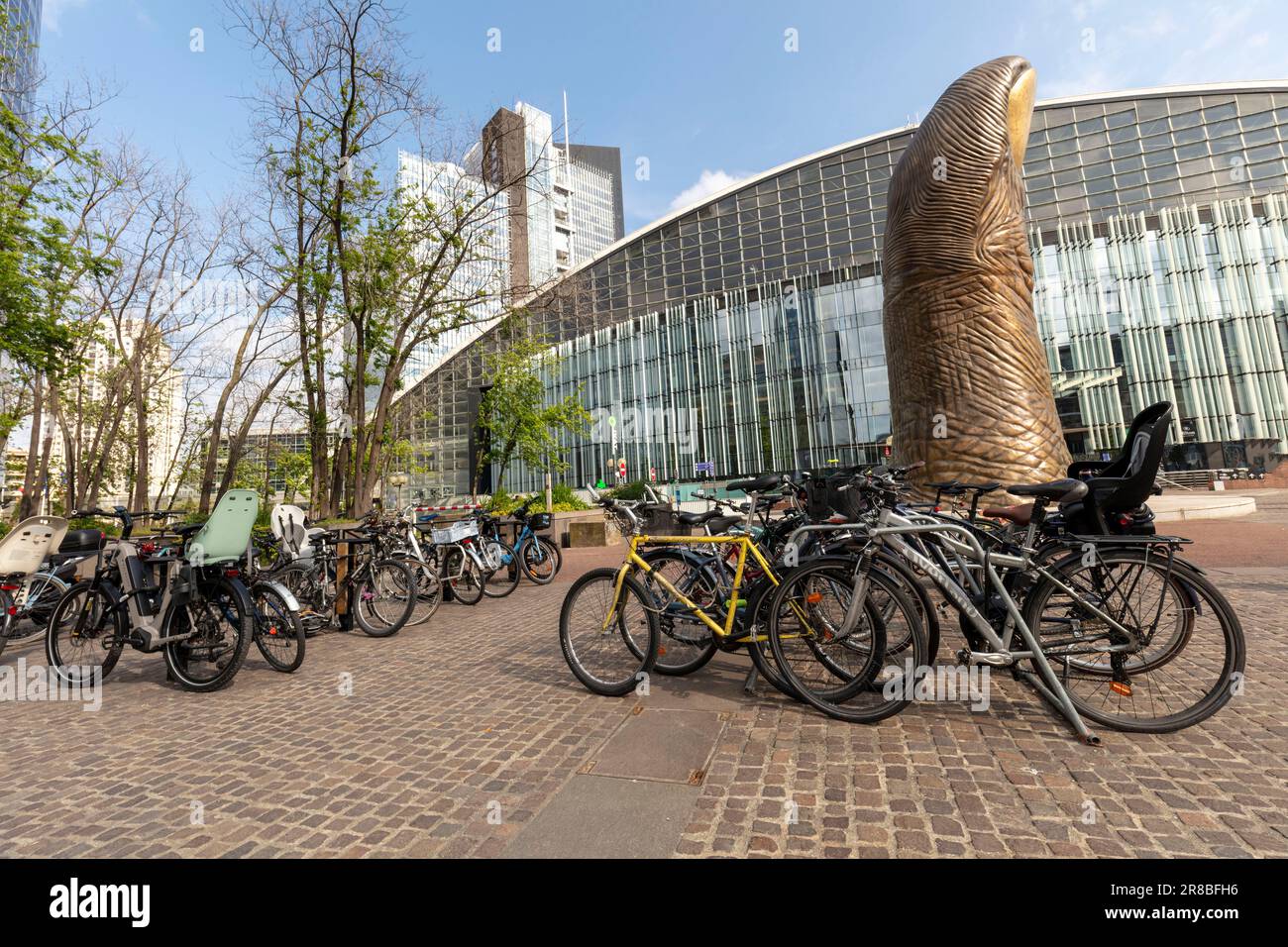 Biciclette ecologiche a Parigi con il pollice gigante a la Défense a metà strada e architettura moderna alle spalle al sole del tardo pomeriggio Foto Stock