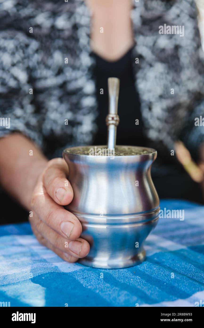 Una donna matura è in piedi con una tazza d'argento nelle sue mani, con il vapore che sale dalla tazza come se contenesse una bevanda calda Foto Stock