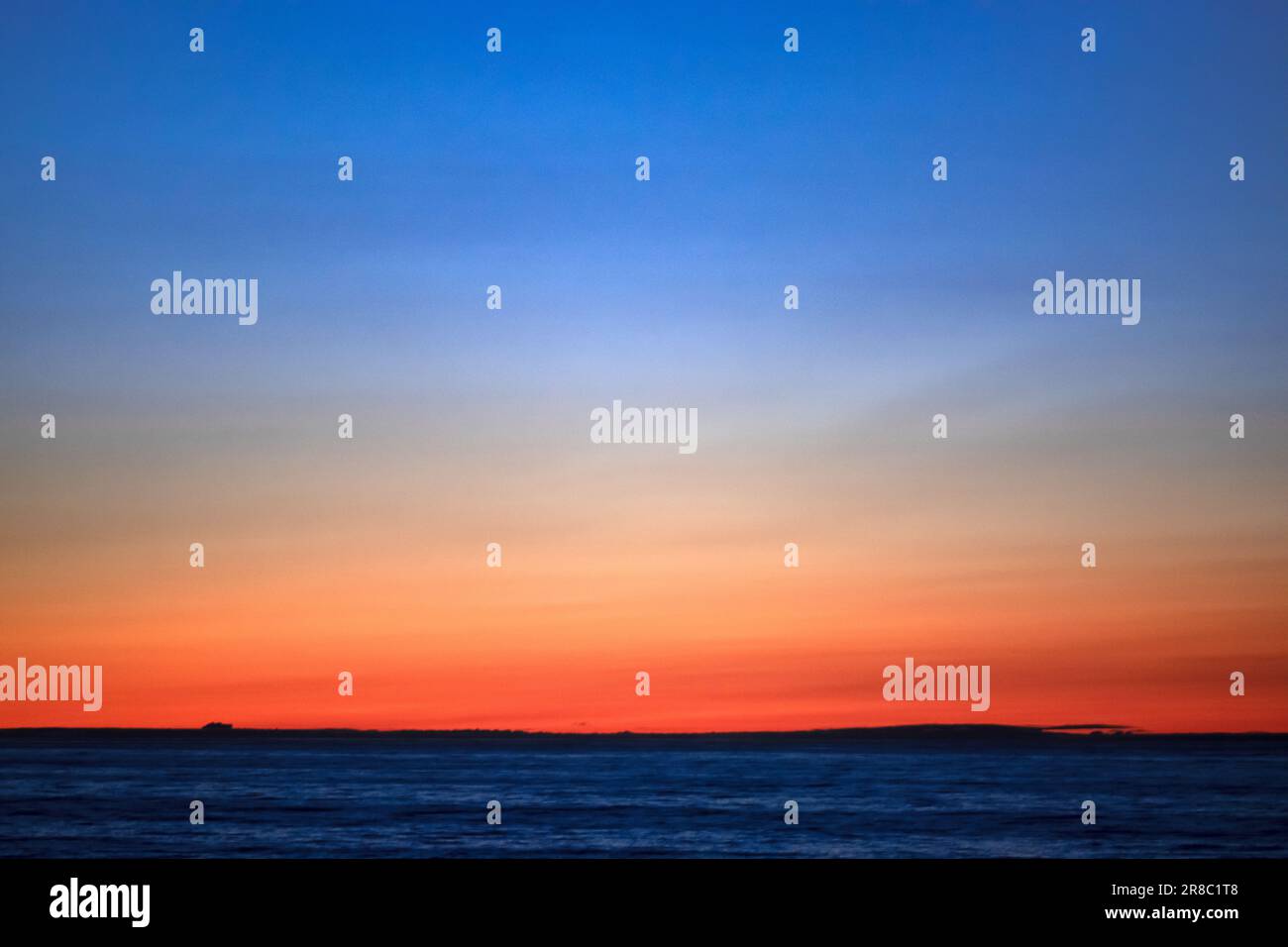 Foto di un tramonto che ha un effetto acquerello con arancio e blu impressionanti all'orizzonte. Foto Stock