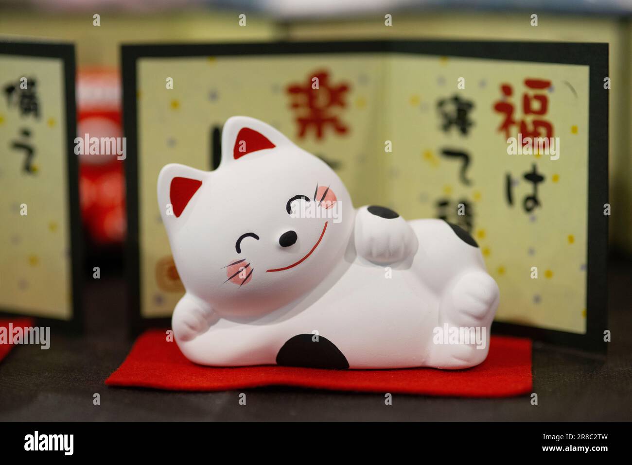 Maneki Neko sdraiato, statue tradizionali di gatti ondeggianti, anche noto come Maneki-neko Foto Stock