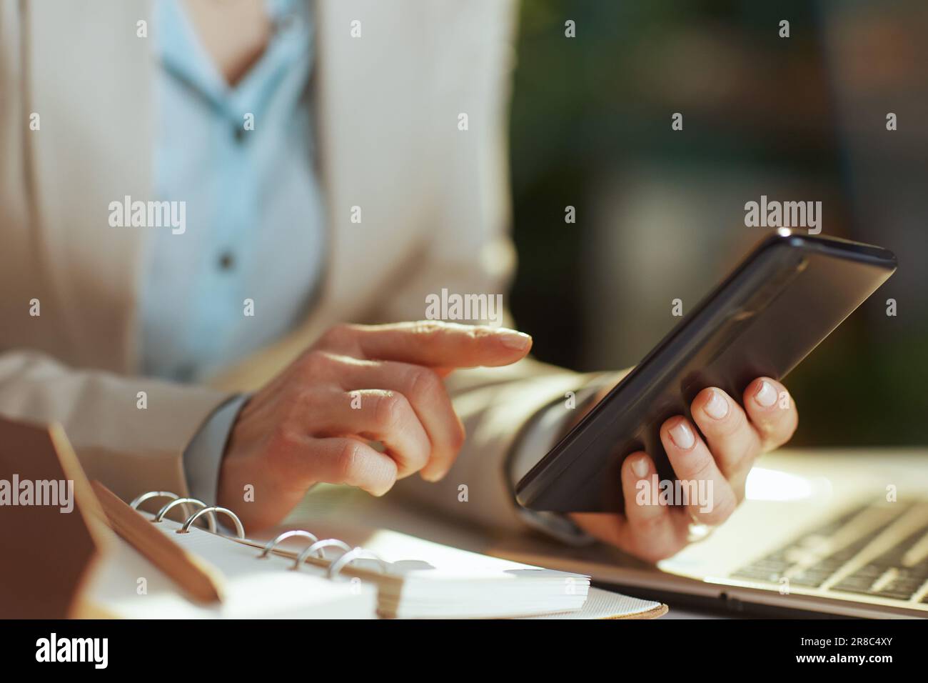 Primo piano su una donna che lavora in un ufficio ecologico utilizzando le applicazioni per smartphone. Foto Stock
