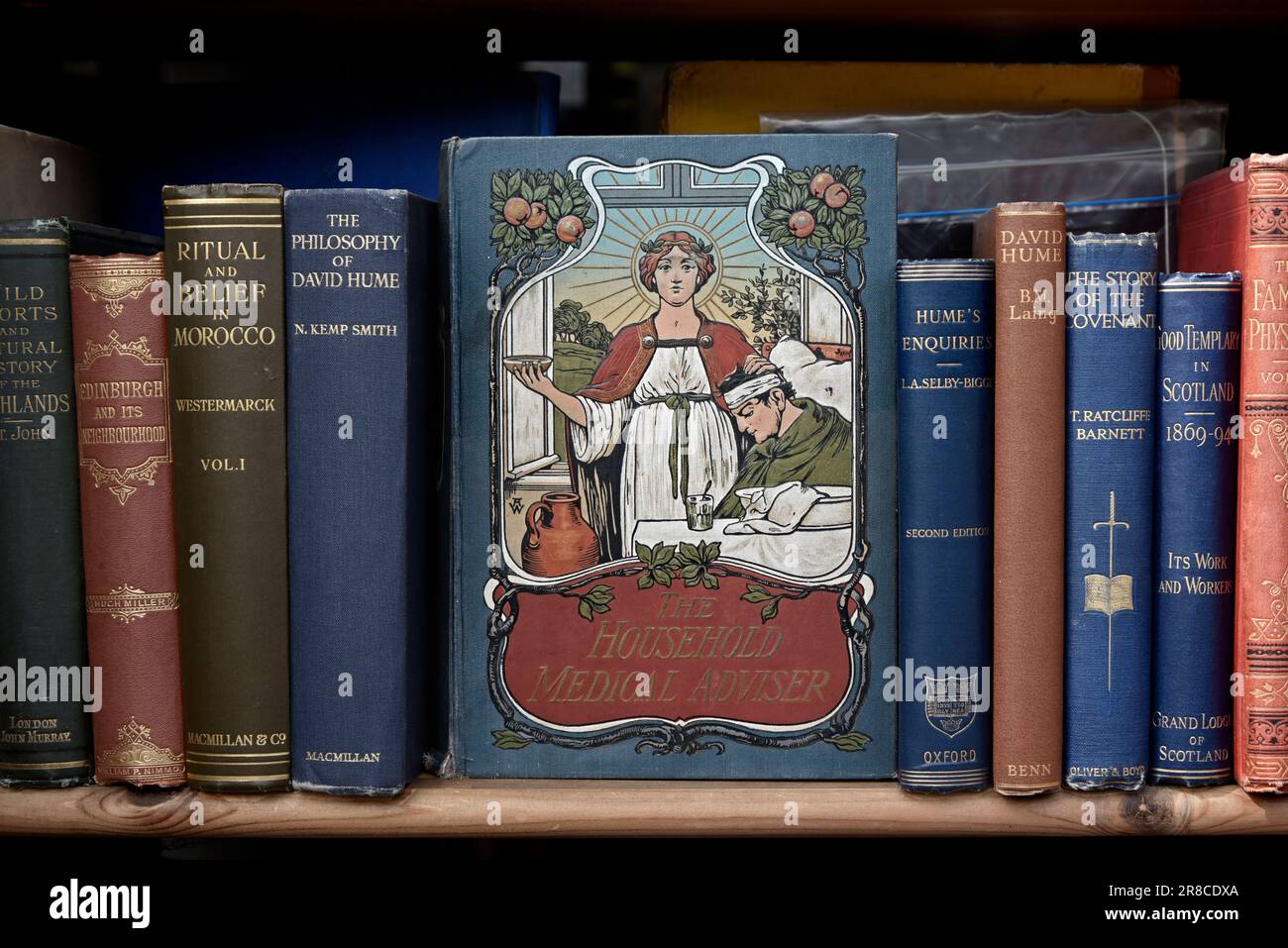 Copia vintage di "The Household Medical Adviser" e di altri libri vintage in mostra nella vetrina di una libreria di seconda mano a Edimburgo, Scozia, Regno Unito. Foto Stock