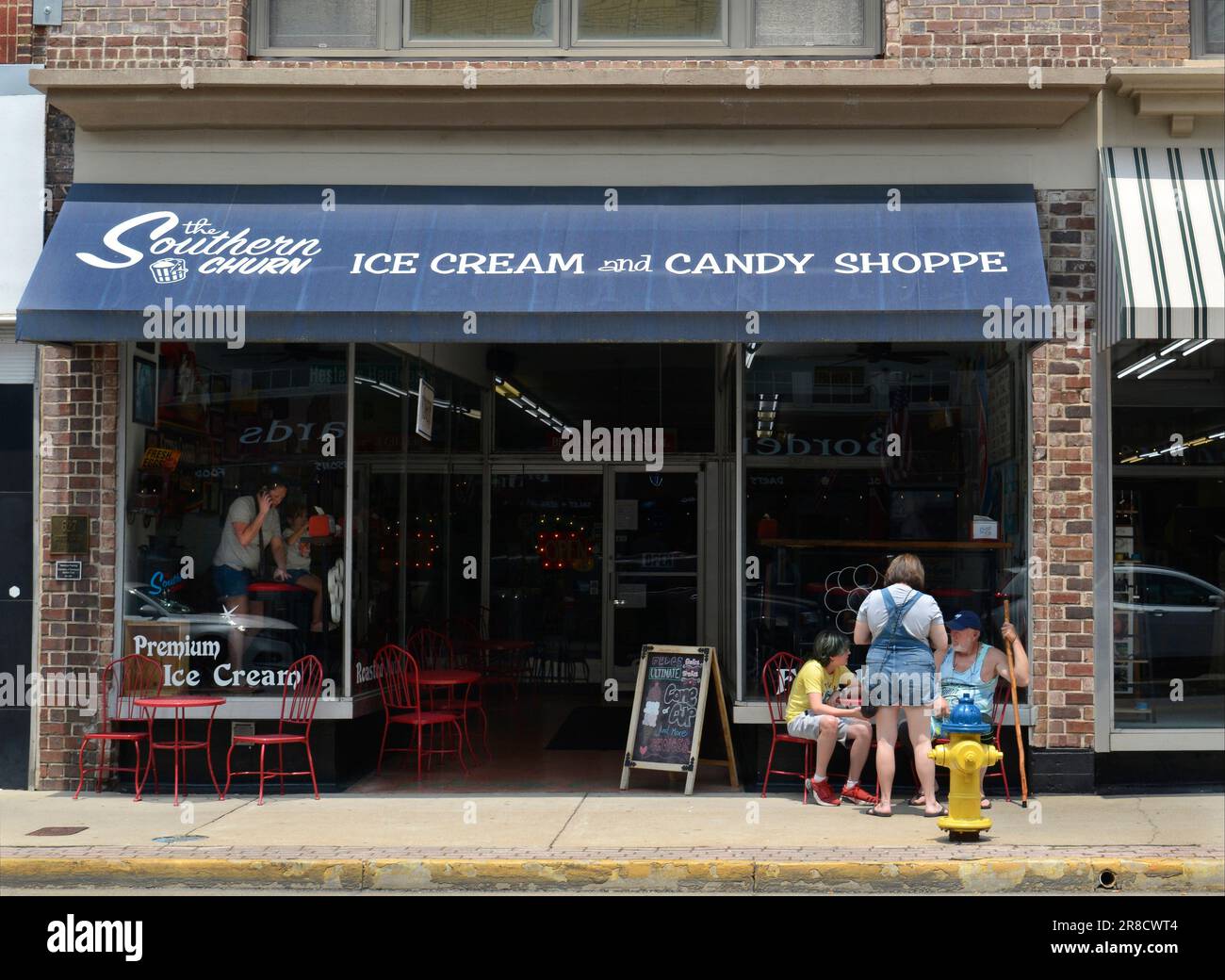 Una scena di strada candida nel centro di Bristol, Virginia, di tre clienti seduti fuori da un negozio di gelati e caramelle lungo la state Street della città. Foto Stock