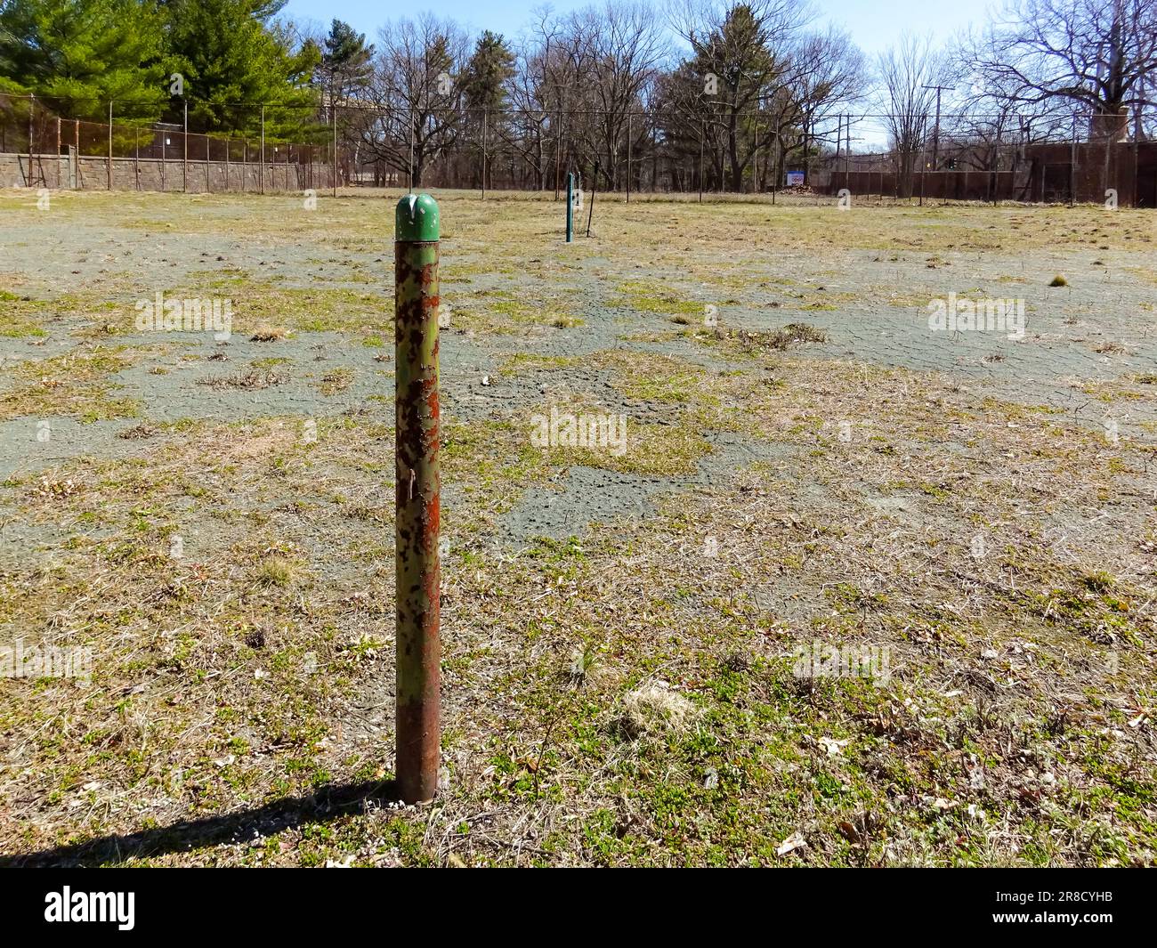 Vecchio campo da tennis abbandonato in terra battuta con palo in rete. Foto Stock