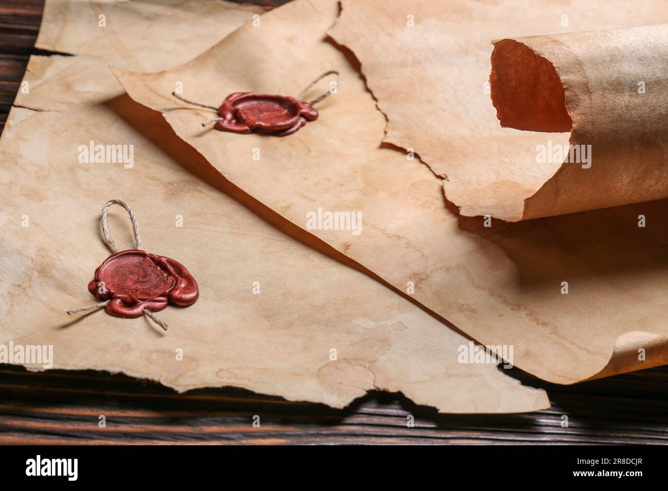 Fogli di vecchia carta pergamena con francobolli di cera su tavola di legno Foto Stock