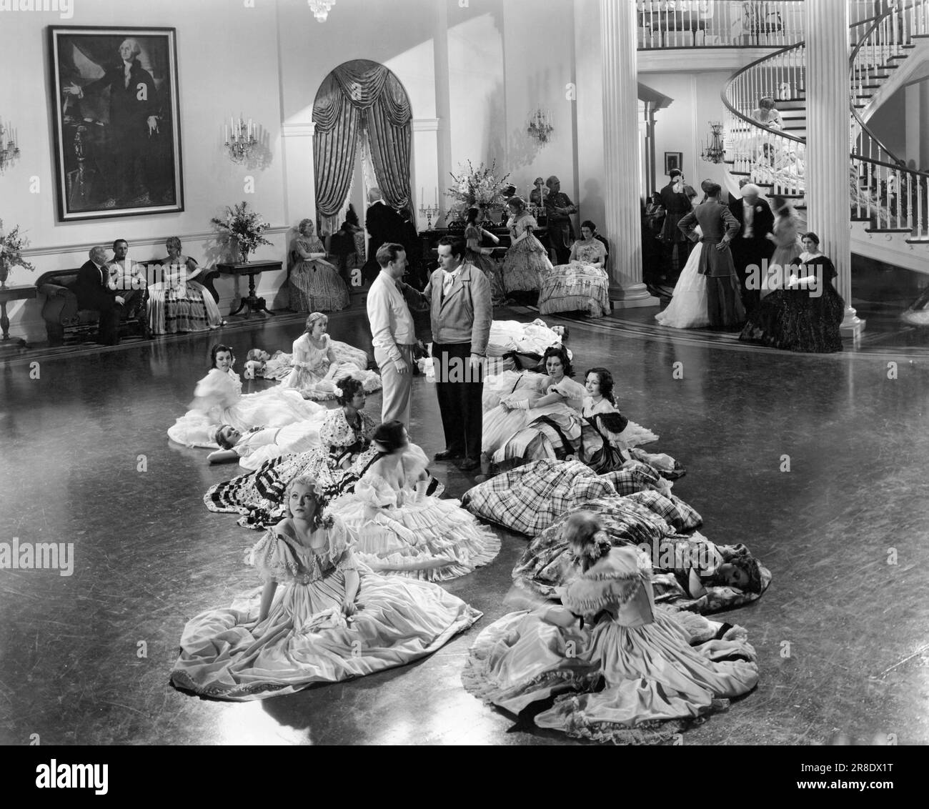 Hollywood, California, 1934 ragazze danzanti riposano sul pavimento della sala da ballo mentre il regista Richard Boleslawski e l'assistente direttore Robert A, Golden map la prossima scena nel nuovo film MGM di Marion Davies, 'Operator 13'. Foto Stock