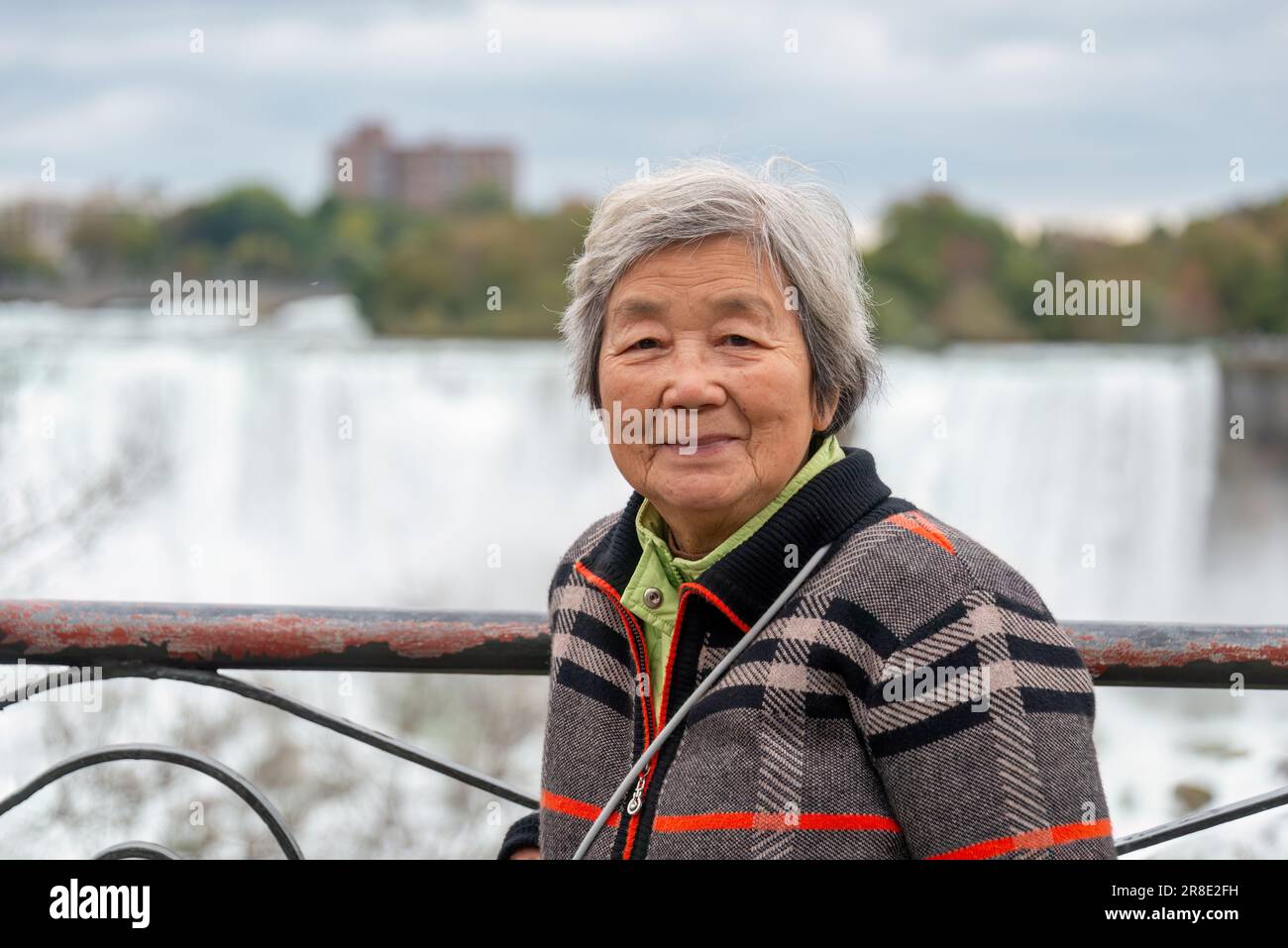 Il turista cinese anziano che si posa per le foto alle cascate del Niagara, Ontario. Canada. Foto Stock