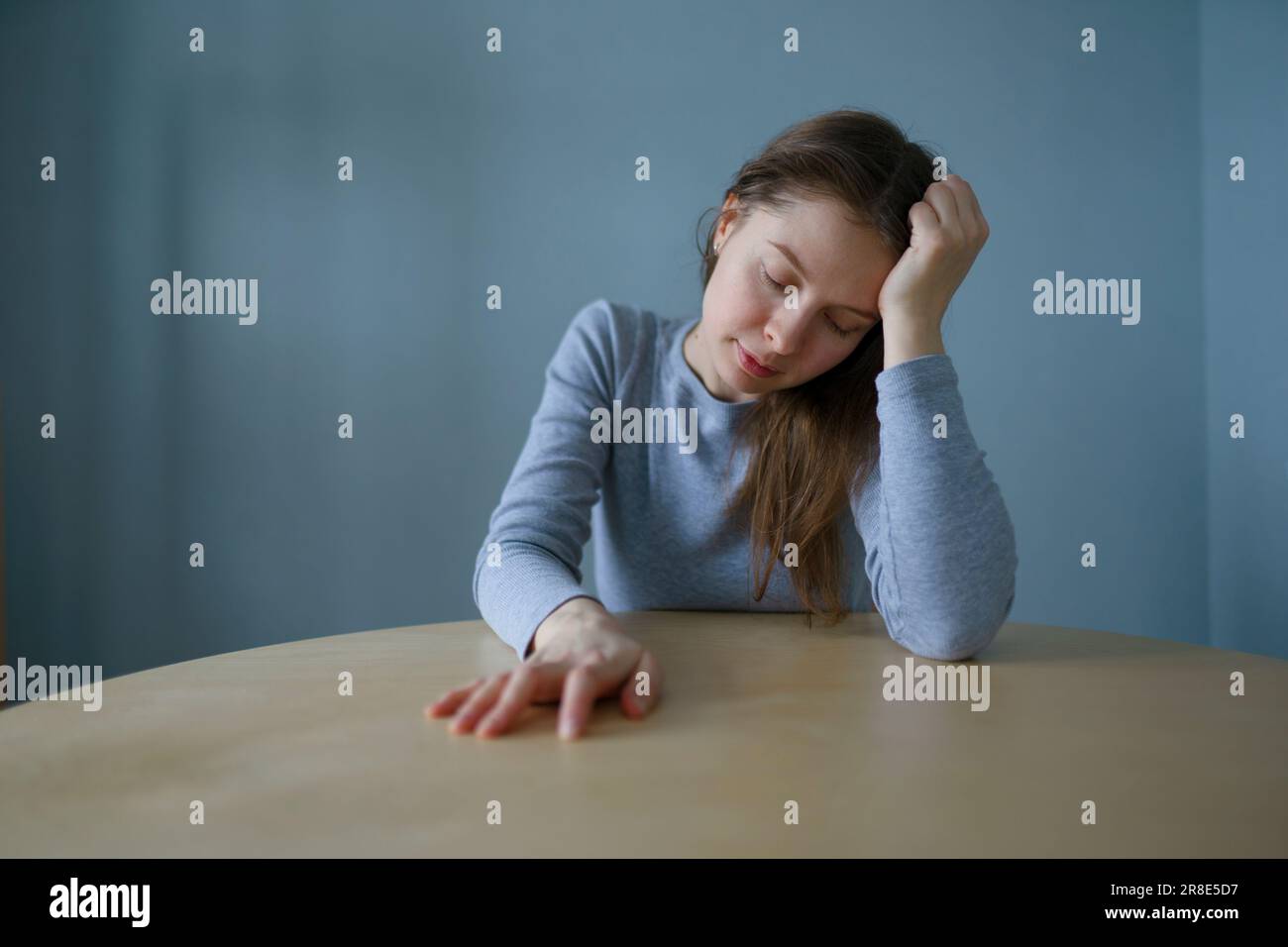 Ritratto di una donna stanca seduta a un tavolo rotondo a casa Foto Stock