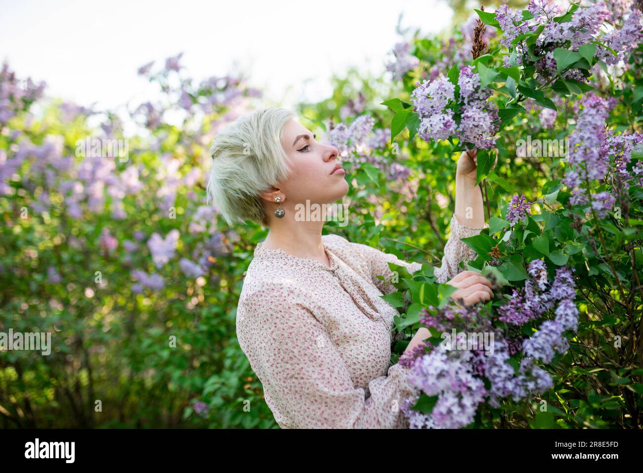 Ritratto di donna che odora fiori lilla in giardino Foto Stock