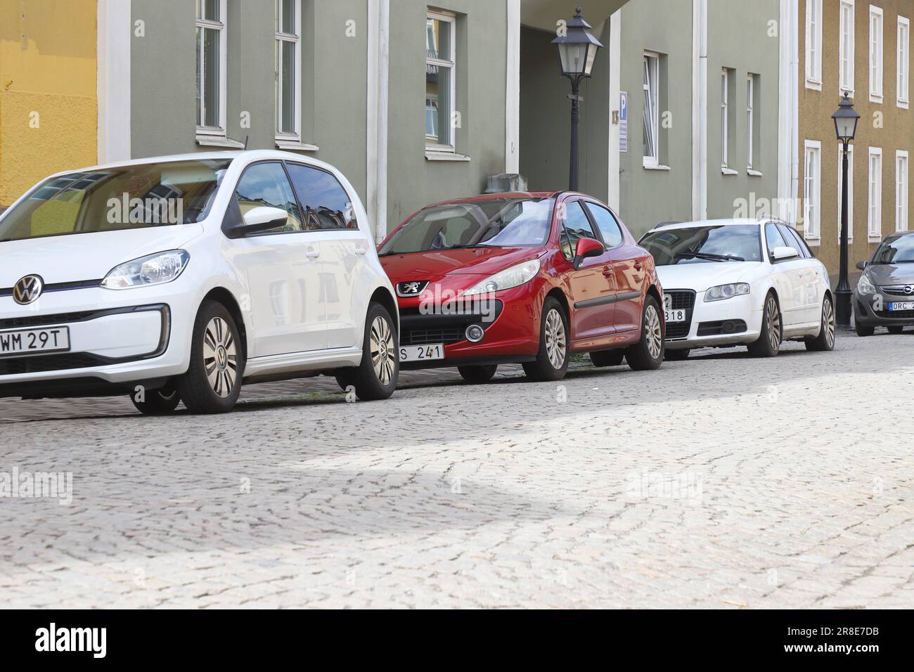 Strangnas, Svezia - 19 giugno 2023: Piccole auto moderne parcheggiate in tasca parcheggiate lungo marciapiedi su strada acciottolata in zona residenziale. Foto Stock