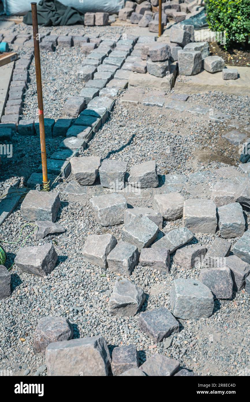 Realizzazione del percorso - pavimentazione di pietre, installazione e posa di pietre da pavimentazione su terrazza, strada o marciapiede. Foto Stock
