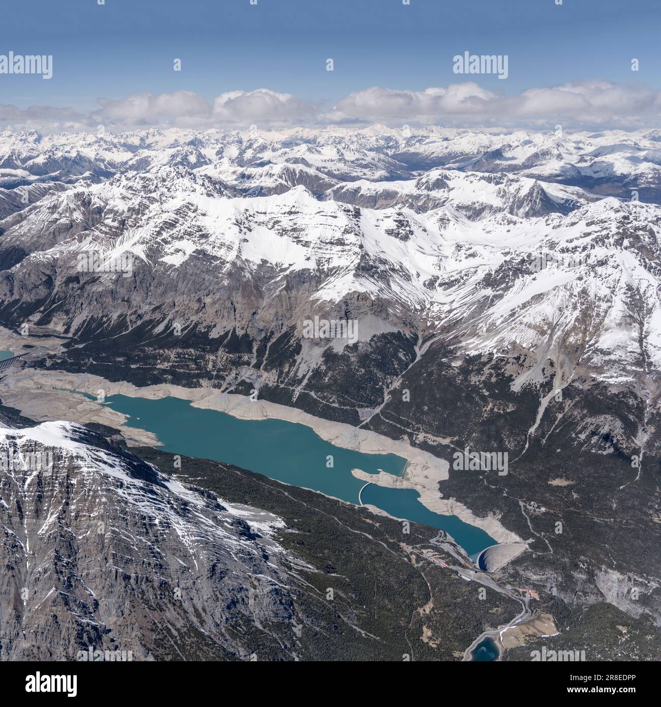 Paesaggio aereo, da un velivolo, di grande diga sul lago di Cancano nella valle di Fraele, girato da sud-ovest in luce di primavera, Sondrio, Italia Foto Stock