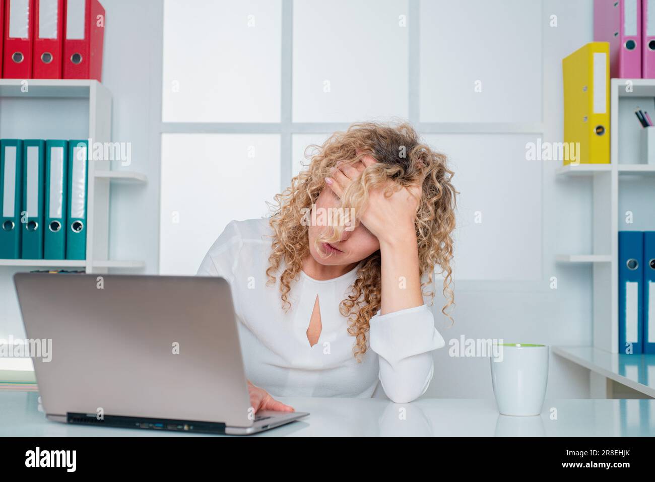 Stanco lavoratore d'ufficio. Donna pigra annoiata che usa il computer portatile la mattina, noiosa in ufficio. Foto Stock