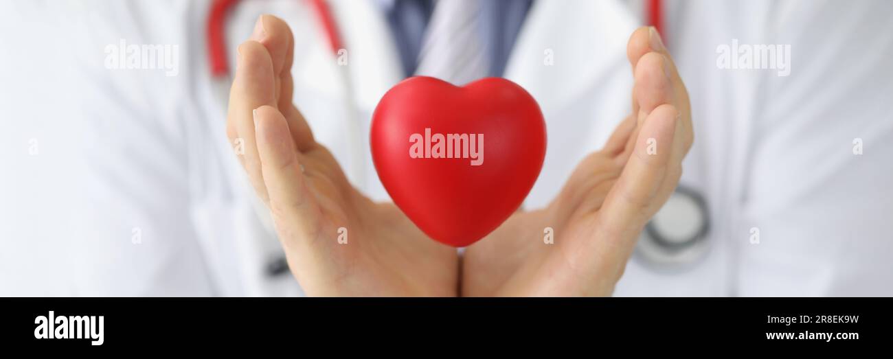 Il cardiologo medico tiene il cuore rosso nell'aria. Trapianto di cuore e malattie cardiovascolari Foto Stock