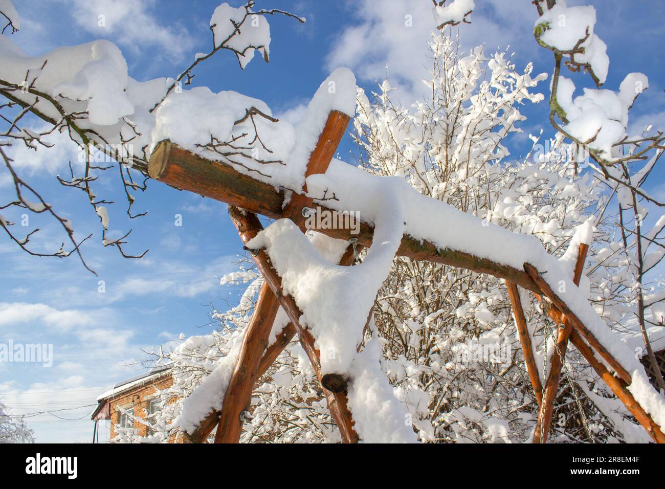 Fiaba invernale nel cortile, altalena da giardino coperta di neve. il giardino di legno oscilla sulle catene, tutto nella neve. Foto Stock