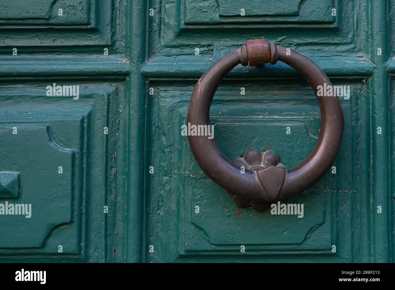 Vecchio battente porta ad anello in bronzo su un portale in legno dipinto di verde Foto Stock