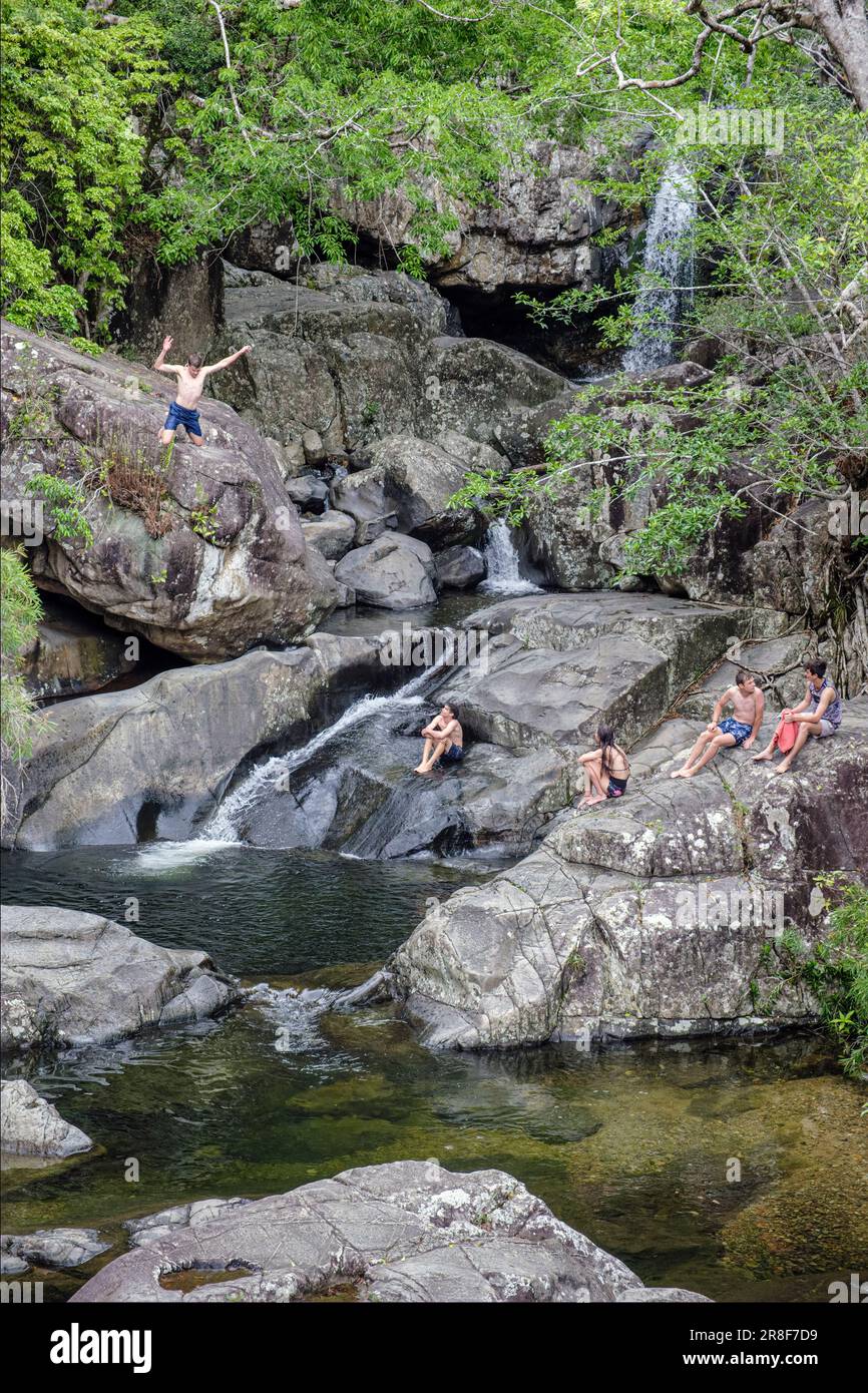 Adolescenti che saltano in una buca di nuoto a Little Crystal Creek, Queensland, Australia Foto Stock