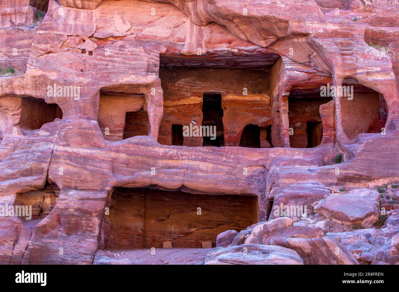 Una scogliera con antiche case scavate nella roccia arenaria di Petra in Giordania. Foto Stock