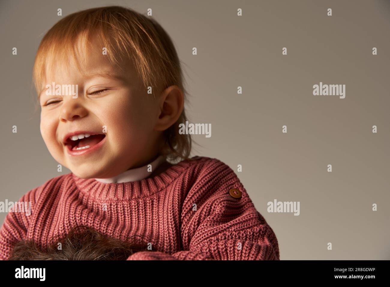 ritratto di ragazza cute del bambino, bambino del toddler, capretto felice in abbigliamento casual sorridente sullo sfondo grigio in studio, emozione, innocenza, moda del toddler Foto Stock