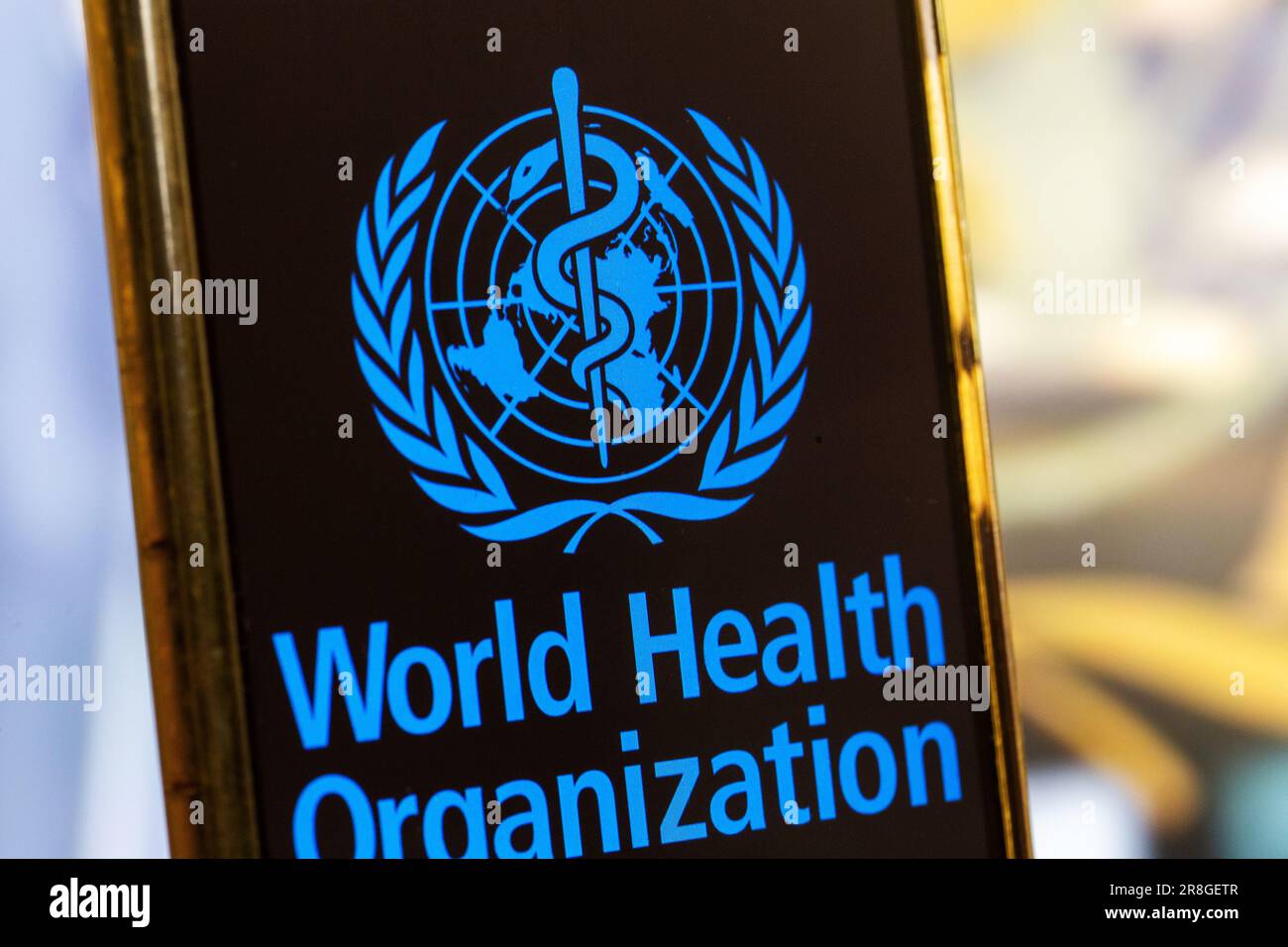 Immagine del simbolo: Smartphone con logo DELL'OMS (Organizzazione mondiale della sanità) su sfondo sfocato Foto Stock