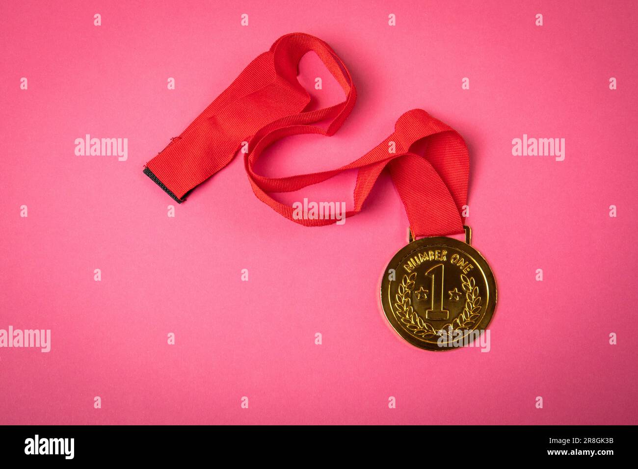 Medaglia d'oro con nastro rosso su sfondo rosa. Foto Stock