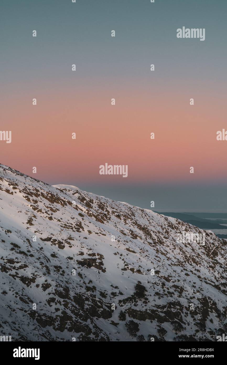 Un maschio adulta caucasico sta sciando su una pista da sci innevata, indossando una giacca scura e un equipaggiamento da sci Foto Stock