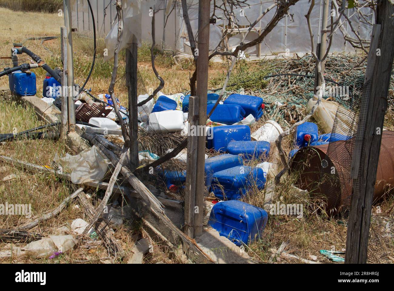 Inquinamento ambientale: taniche di plastica vuote in cui i pesticidi venivano immagazzinati in una serra fatiscente Foto Stock