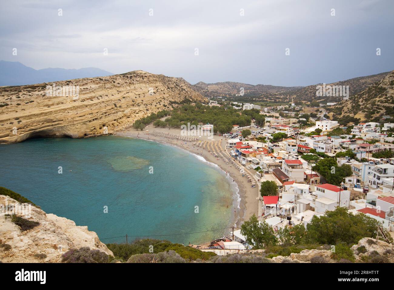 Vista su Matala, Creta, con la spiaggia e il mare, circondati da rocce calcaree con grotte sul lato ovest, scavate in pietra calcarea Foto Stock