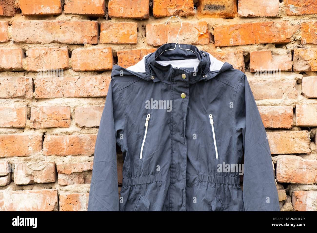 giacca donna blu pesa su grucce sulla parete a casa all'aperto, giacca donna moda Foto Stock